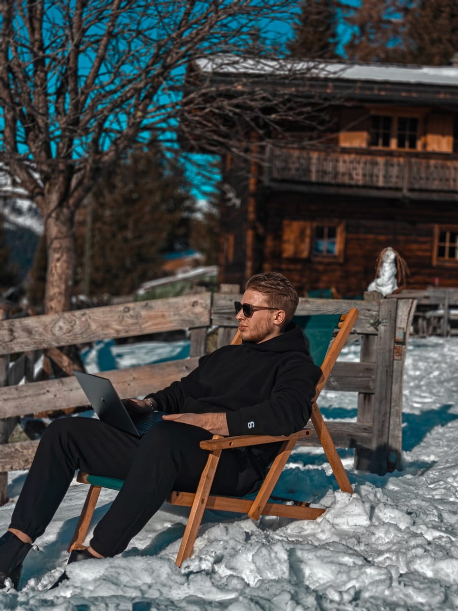 Arbeiten mit Laptop im Schnee vor einer Berghütte